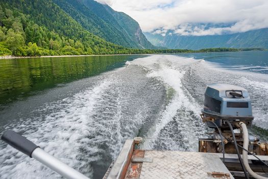 view of the landscape of the coast, the coastal strip of the lake with steep misty rocks of the mountains from the departing motor boat