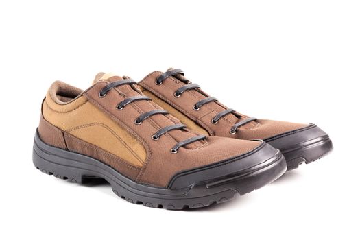a pair of cheap brown fabric hiking or hunting shoes with elastic rubber laces isolated on white background.