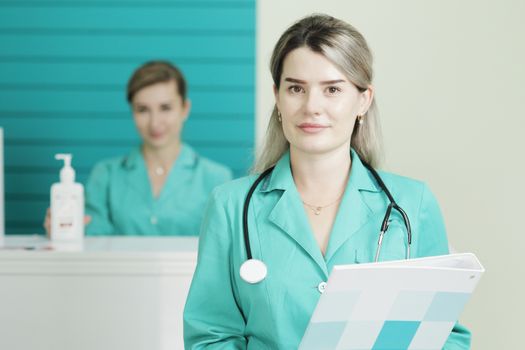Two female doctors or nurses looking at the camera. Stethoscope phonendoscope on the neck. Holds a folder in his hands