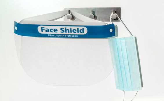 PPE supplies face shield direct splash protection and mask hanging on hooks. New clean corona virus protective equipment ready to use for coronavirus prevention.