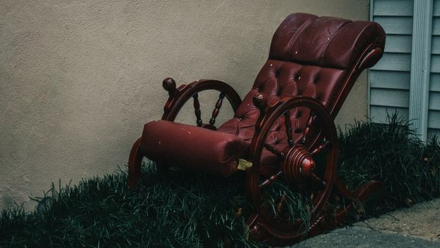 An Old-Fashioned Cushioned Red Rocking Chair Sitting in a Patch of Grass Next to a Building