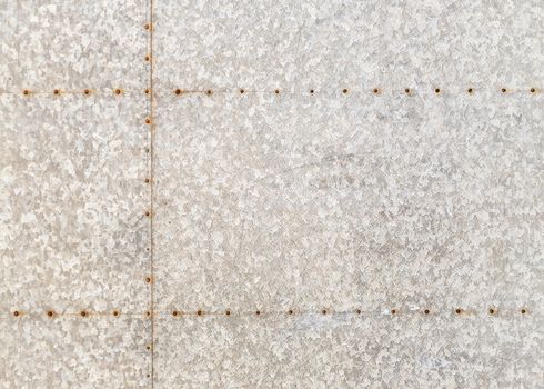 Background of an old marbled metal sheet with rusty rivets.