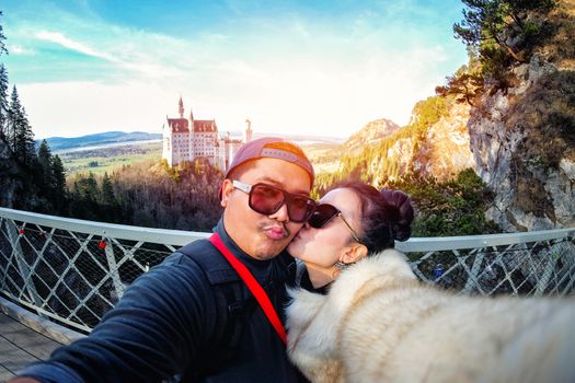 Young Couple Tourists selfie with mobile phone near the Neuschwanstein Castle at daylight in Germany