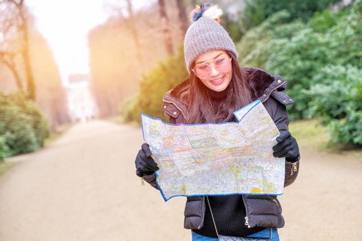 Young female tourist with map looking for a way to Sans Souci palace in Potsdam, Berlin, Germany, Europe.