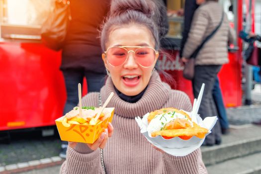 Young Woman Eating A  French Fries and salmon Street food in Germany