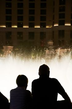 Night scene with silhouettes of people admiring the Bellagio fountains spectacle at Las Vegas