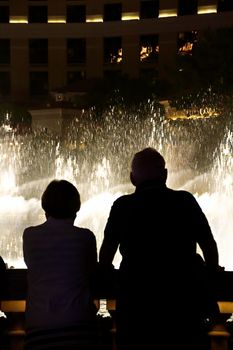 Night scene with silhouettes of people admiring the Bellagio fountains spectacle at Las Vegas