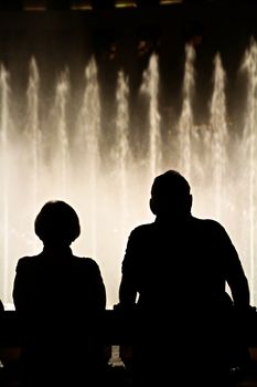 Night scene with silhouettes of people admiring the Bellagio fountains spectacle at Las Vegas