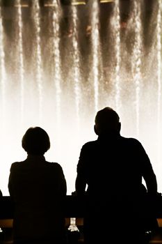 Night scene with silhouettes of people admiring the Bellagio fountains spectacle at Las Vegas