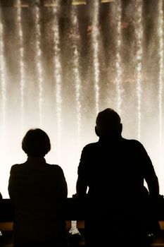 Night scene with silhouettes of people admiring the Bellagio fountains spectacle at Las Vegas