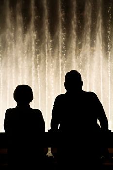 Night scene with silhouettes of people admiring the Bellagio fountains spectacle at Las Vegas