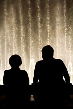 Night scene with silhouettes of people admiring the Bellagio fountains spectacle at Las Vegas