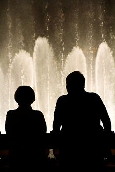 Night scene with silhouettes of people admiring the Bellagio fountains spectacle at Las Vegas