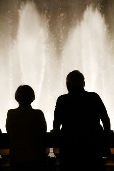 Night scene with silhouettes of people admiring the Bellagio fountains spectacle at Las Vegas