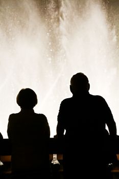 Night scene with silhouettes of people admiring the Bellagio fountains spectacle at Las Vegas