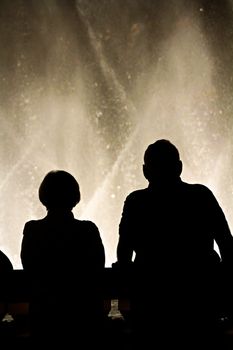 Night scene with silhouettes of people admiring the Bellagio fountains spectacle at Las Vegas