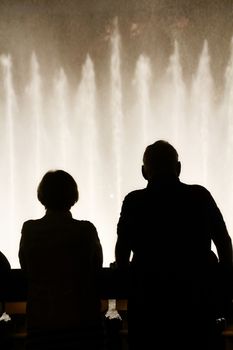 Night scene with silhouettes of people admiring the Bellagio fountains spectacle at Las Vegas