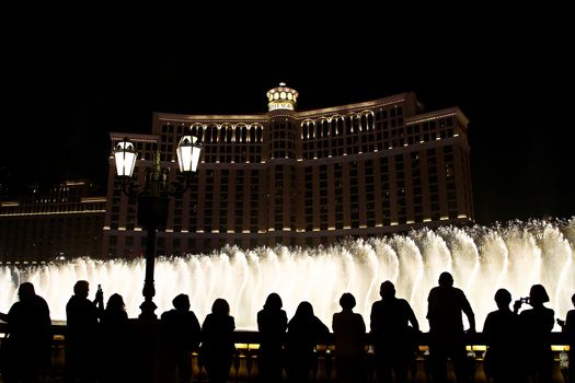 Night scene with silhouettes of people admiring the Bellagio fountains spectacle at Las Vegas