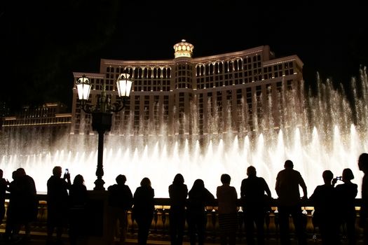 Night scene with silhouettes of people admiring the Bellagio fountains spectacle at Las Vegas