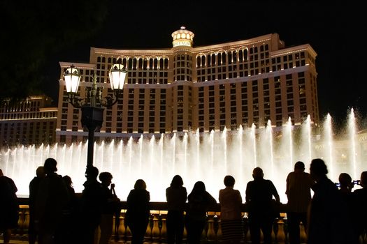 Night scene with silhouettes of people admiring the Bellagio fountains spectacle at Las Vegas