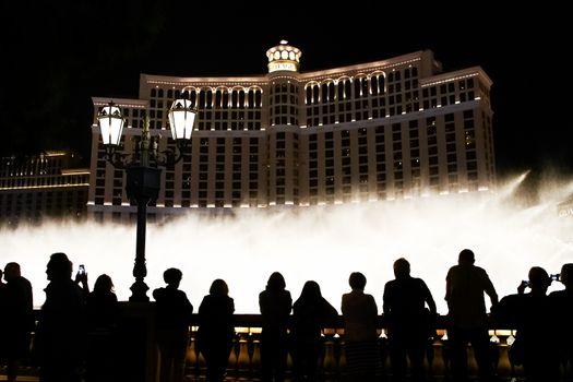 Night scene with silhouettes of people admiring the Bellagio fountains spectacle at Las Vegas