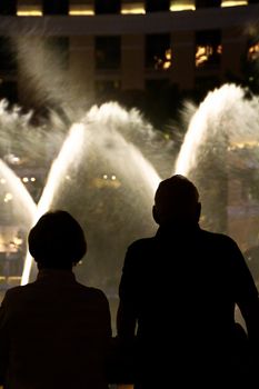 Night scene with silhouettes of people admiring the Bellagio fountains spectacle at Las Vegas