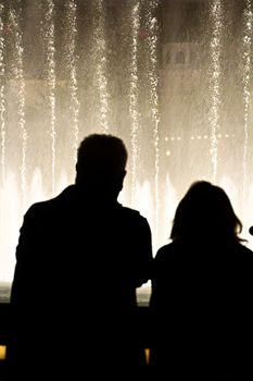 Night scene with silhouettes of people admiring the Bellagio fountains spectacle at Las Vegas