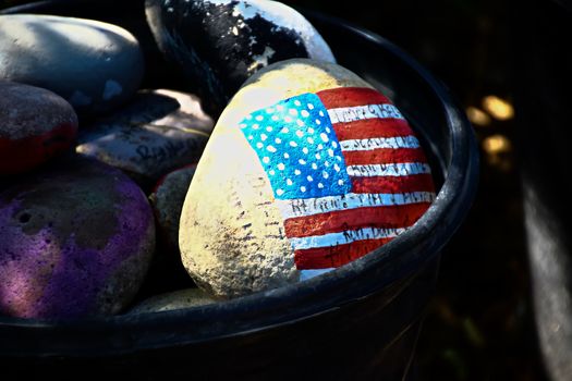 rock painted with the American Flag.American flag painted on a gray stone.Close-up of rock with American flag painted.