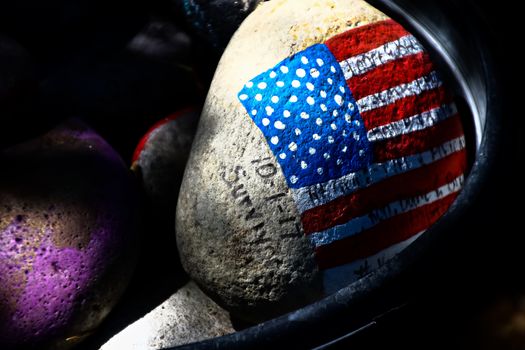 rock painted with the American Flag.American flag painted on a gray stone.Close-up of rock with American flag painted.