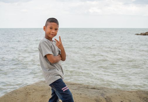 A boy standing on a rock with a sea background