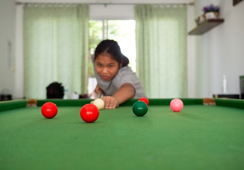 Asian woman playing snooker By aiming at his queue. Focus on the red ball.