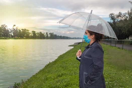 Real woman watching the sunset on a lake. face mask, new normal