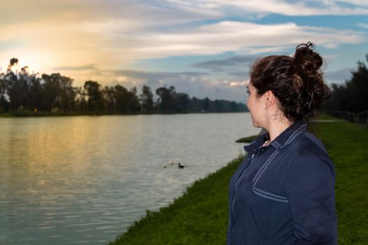 Real woman watching the sunset on a lake. summer