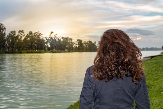 Real woman watching the sunset on a lake. summer