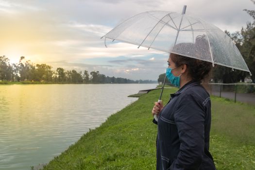 Real woman watching the sunset on a lake. face mask, new normal