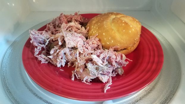 hamburger with bun and pulled pork on red plate in microwave