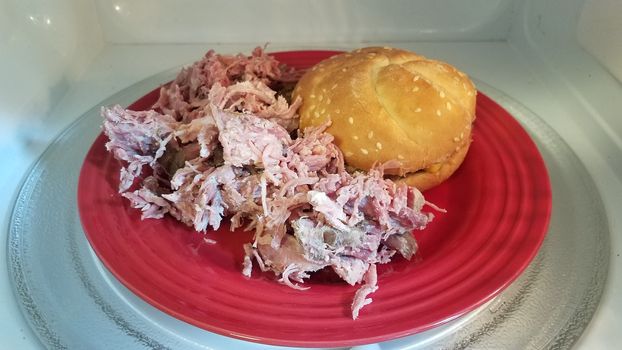 hamburger with bun and pulled pork on red plate in microwave