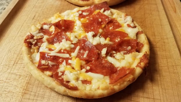 small pepperoni and cheese pizza on wood cutting board