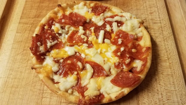small pepperoni and cheese pizza on wood cutting board