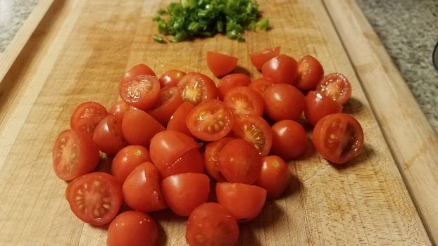 red tomatoes on cutting board with chives or onions