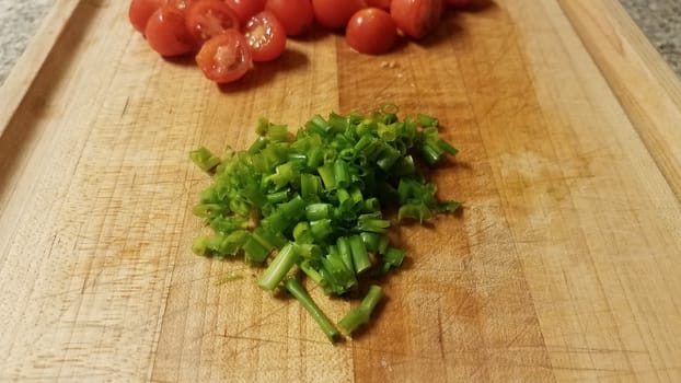 green chives or onion and red tomatoes on cutting board