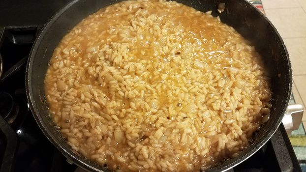 risotto italian rice with gravy and onion in skillet or frying pan