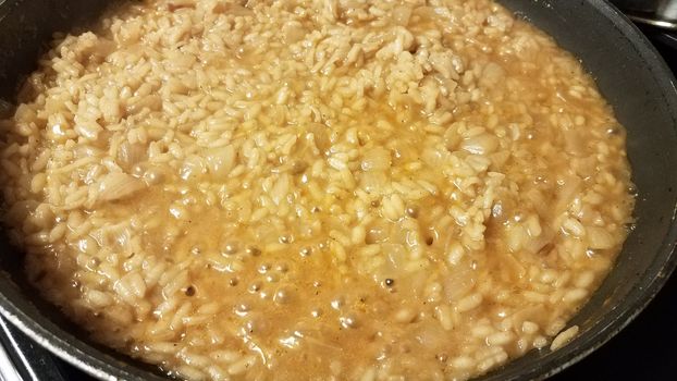 risotto italian rice with gravy and onion in skillet or frying pan