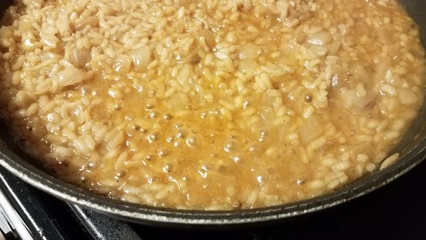 risotto italian rice with gravy and onion in skillet or frying pan