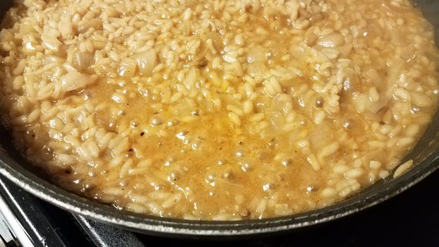 risotto italian rice with gravy and onion in skillet or frying pan