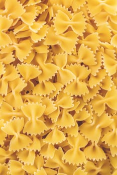 Italian pasta vertical background. Uncooked "bow-tie pasta" (farfalle).