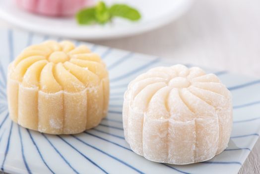 Colorful snow skin moon cake, sweet snowy mooncake, traditional savory dessert for Mid-Autumn Festival on bright wooden background, close up, lifestyle.