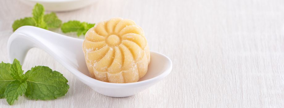 Colorful snow skin moon cake, sweet snowy mooncake, traditional savory dessert for Mid-Autumn Festival on bright wooden background, close up, lifestyle.