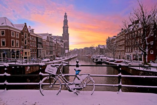 City scenic from snowy Amsterdam with the Westerkerk in the Netherlands at sunset