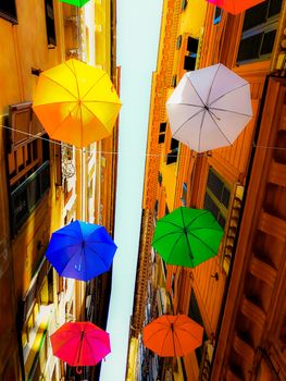 Genova, Italy - 0/29/2020: Multicolored umbrellas against the sky, street decorated. LGBT flag. Rainbow love concept. Human rights and tolerance.